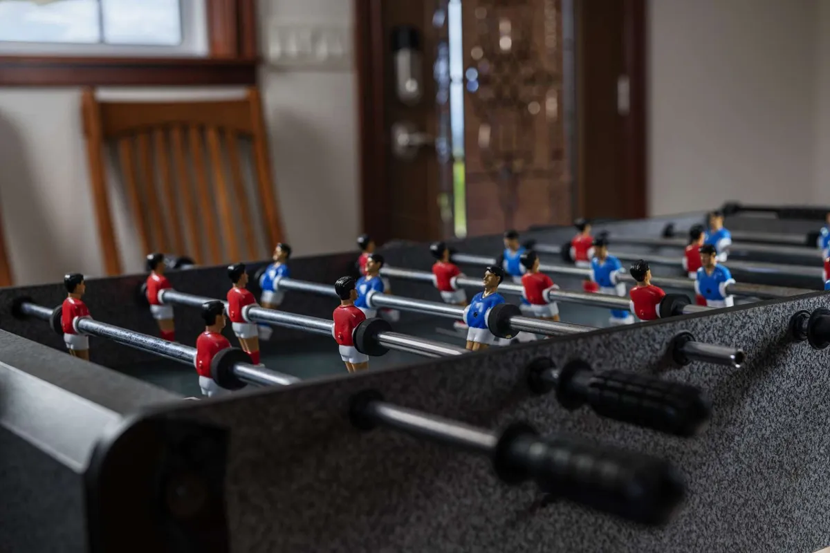 A foosball table set up in a bright room near the front door, with a wooden chair and natural light streaming in. The playful setup hints at fun, social activities for groups and adds a vibrant note to the home environment.