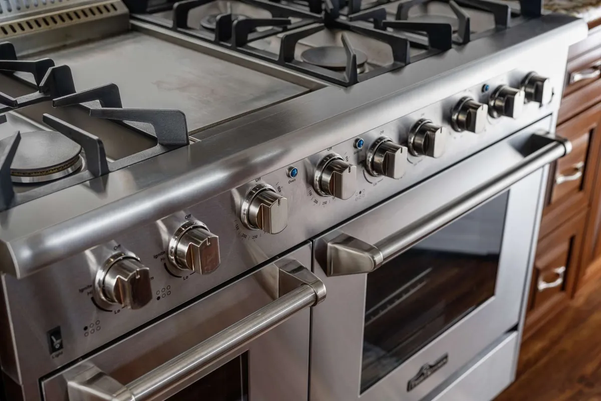 A modern kitchen featuring a high-end gas stove with multiple burners and a griddle surface, suggesting the space is well-equipped for preparing large meals or catering for events. The design is sleek and functional, ideal for group cooking or bringing in local caterers.